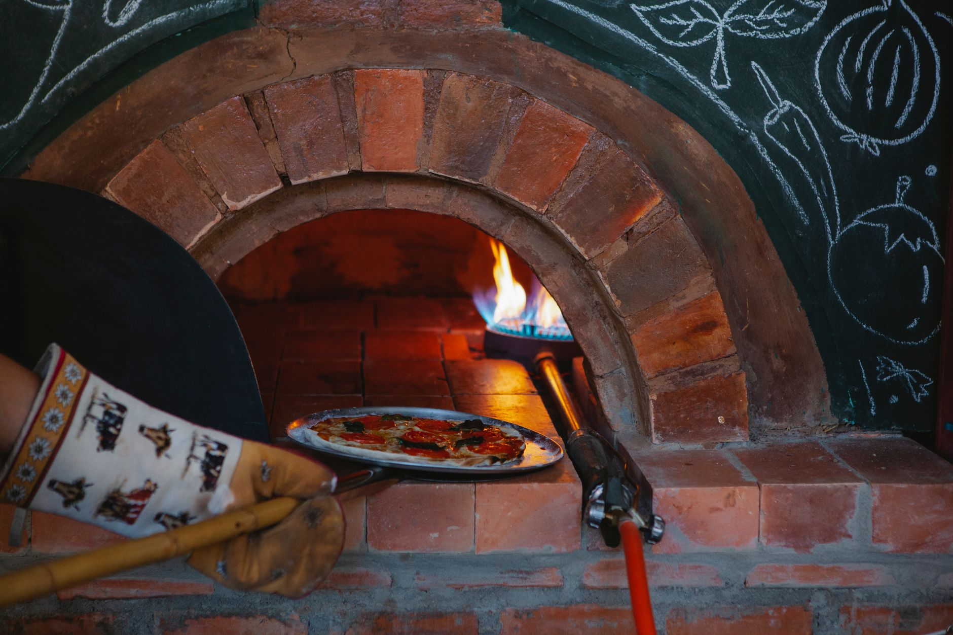 Pizza sendo assada no forno a lenha